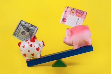 100 dolarlık banknotu olan bir domuz kumbarası, denge tahtasındaki 100 Yuan 'lık bir kumbaradan daha ağır basar.