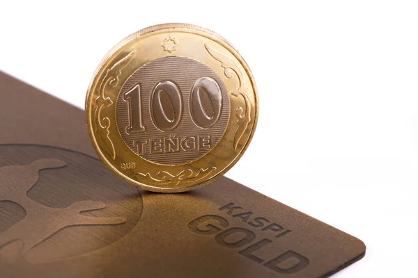 Almaty, Kazakistan, 08.02.2021. 100 Kazakistan senedi değerinde bir sikke Kaspi Bankası 'nın avuç içi kartının bir parçasında kenarda duruyor.