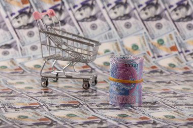 10,000 Kazakistan tenge faturası ve bir alışveriş arabası 100 dolarlık banknotlara karşı.
