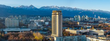 Almaty, Kazakistan. 11.02.2025. Almaty, Kazakistan 'ın merkez kısmının insansız hava aracı görüntüsü, Kazakistan Oteli ile birlikte Trans-Ili Alatau Dağları' nın tepesinde bir sonbahar sabahı.