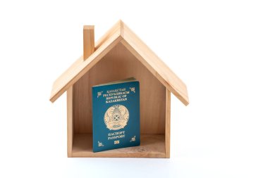 Kazakistan Cumhuriyeti vatandaşının pasaportu ve beyaz arka planda sembolik ahşap bir ev.