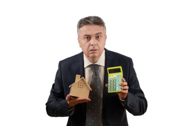 Sembolik ahşap bir ev ve hesap makinesi tutan orta yaşlı bir adamın yer aldığı bir emlak acentesinin kavramsal hikayesi..