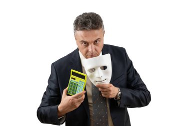 Takım elbiseli orta yaşlı bir adam elinde beyaz bir maske ve hesap makinesi tutuyor.