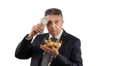 Orta yaşlı bir adam altın bir boğa ve bir dolarlık banknotlar tutuyor..