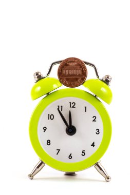 Beyaz arka planda bir Amerikan sikkesi ve çalar saat.