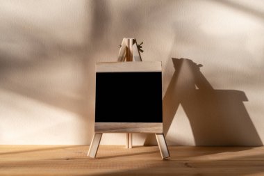 Tahta üzerine siyah karatahta. Duvarın arkasında gölgeli duruyor.