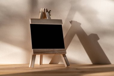 Tahta üzerine siyah karatahta. Duvarın arkasında gölgeli duruyor.