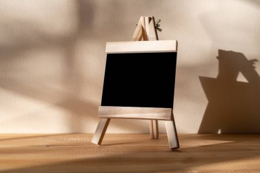 Tahta üzerine siyah karatahta. Duvarın arkasında gölgeli duruyor.