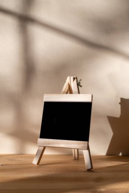 Tahta üzerine siyah karatahta. Duvarın arkasında gölgeli duruyor.