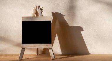 Tahta üzerine siyah karatahta. Duvarın arkasında gölgeli duruyor.