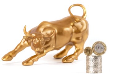 Borsada iyimserliğin yanı sıra zenginlik ve açgözlülüğün sembolü olan altın bir boğa (dana) ve 1 ve 100 Kazakistan parası.