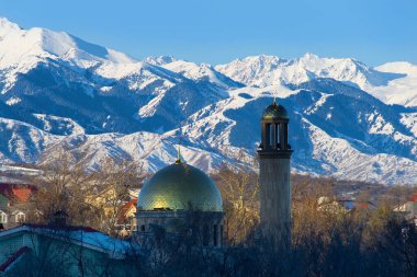 Kazak şehri Almaty 'deki küçük bir caminin kubbesi ve minaresi bir bahar sabahı bir dağ sırasının arka planına karşı..
