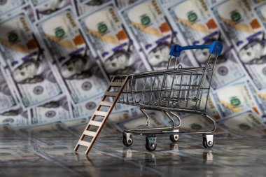 Arkasında 100 dolarlık banknotlar olan boş bir süpermarket arabası.