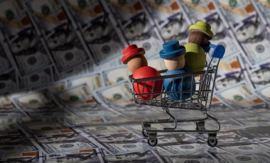 Minyatür bir alışveriş arabasındaki sembolik ahşap insanlar 100 dolarlık banknotlara karşı.