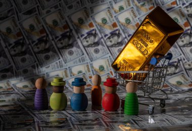 Minyatür bir alışveriş arabasındaki altın külçenin arkasında 100 dolarlık banknotlar var.