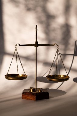 Adaletin altın pulları uzun gölgeli bir duvara karşı