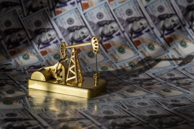 100 dolarlık banknotların arka planına karşı altın bir petrol pompası.