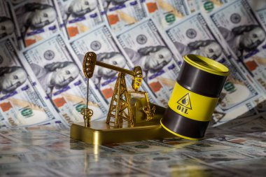 Altın bir yağ pompası ve demir varil 100 dolarlık banknotlara karşı.