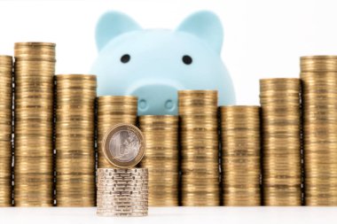 1 Avro para, domuz kumbarası ve beyaz arka planda yığınla bozuk para.