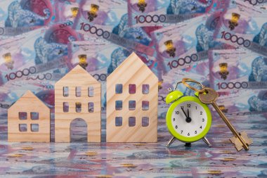 Çalar saat, altın bir daire anahtarı ve 10.000 Kazakistan 'ın onluk banknotlarına karşı sembolik ahşap evler..