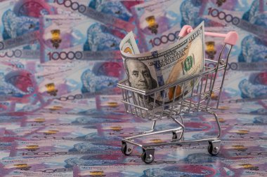 Bir süpermarket alışveriş arabasında 100 dolarlık fatura, arka planda 10.000 adet Kazakistan banknotuna karşı.