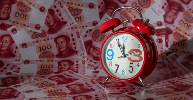 100 Çin Yuan 'ının arka planına karşı kırmızı bir çalar saat.