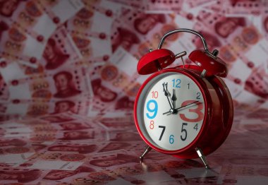 100 Çin Yuan 'ının arka planına karşı kırmızı bir çalar saat.