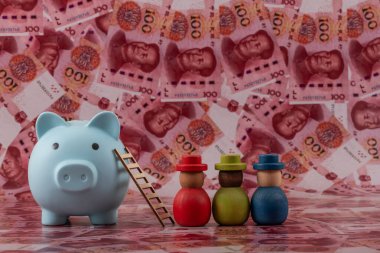 Sembolik ahşap insanlar ve arka planda 100 Çin Yuan 'ı olan bir kumbara..