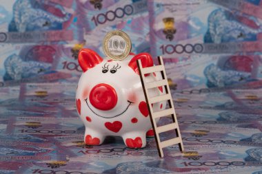 Bir domuz kumbarası ve 100 Kazakistan madeni parasına karşılık 10.000 tenge banknot..