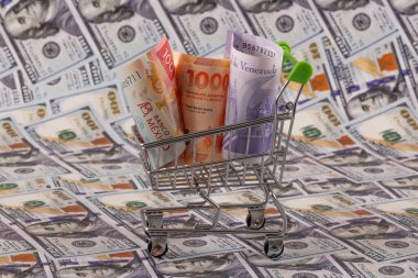 Latin Amerika ülkelerinden banknotlar - Meksika, Venezuela ve Arjantin - minyatür bir alışveriş arabasında 100 dolarlık banknotlara karşı