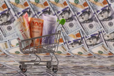 Latin Amerika ülkelerinden banknotlar - Meksika, Venezuela ve Arjantin - minyatür bir alışveriş arabasında 100 dolarlık banknotlara karşı