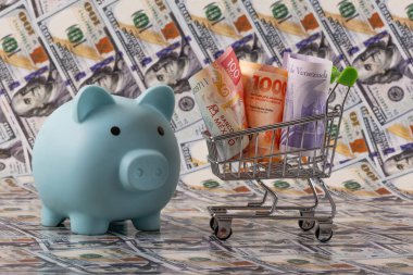 Latin Amerika ülkelerinden banknotlar - Meksika, Venezuela ve Arjantin - minyatür bir alışveriş arabasında 100 dolarlık banknotlara karşı