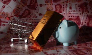 Bir altın külçesi ve bir domuz kumbarası 100 Çin yuan banknotuna karşı.