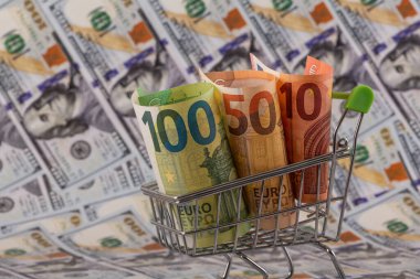 Bir alışveriş arabasındaki 10, 50 ve 100 avroluk banknotlar 100 dolarlık banknotlara karşı.