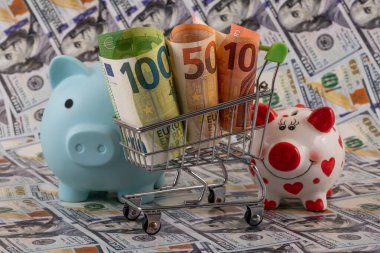 10, 50 ve 100 avroluk banknotlar bir alışveriş arabasında ve bir kumbarada 100 dolarlık banknotlara karşı.