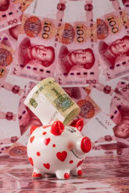 100 Çin yuan banknotunun arka planında insan kalbi sembolü olan komik bir kumbara..