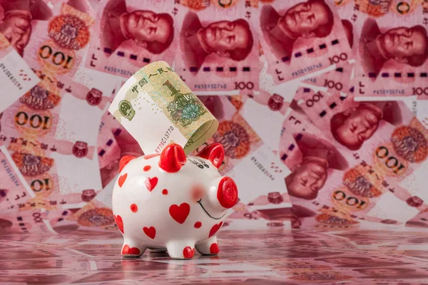 100 Çin yuan banknotunun arka planında insan kalbi sembolü olan komik bir kumbara..