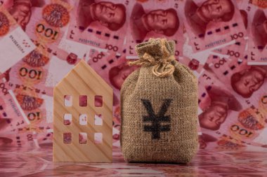 İçinde Çin Yuan sembolü ve sembolik minyatür bir ev olan bir para çantası 100 Yuan 'lık banknotlarla dolu..