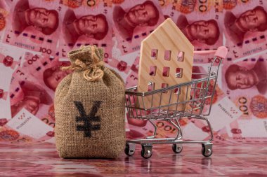 İçinde Çin Yuan sembolü ve sembolik minyatür bir ev olan bir para çantası 100 Yuan 'lık banknotlarla dolu..