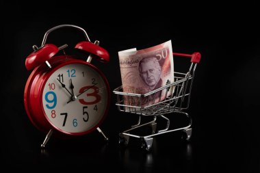 50 sterlinlik banknot ve siyah bir arkaplanda çalar saat.