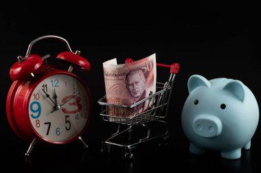 50 sterlinlik banknot ve siyah bir arkaplanda çalar saat.