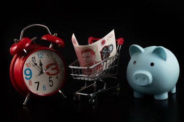 50 sterlinlik banknot ve siyah bir arkaplanda çalar saat.