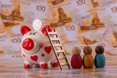 Bir domuz kumbarası ve üzerinde Rus rublesi sembolü olan bir sikke 100 Rus rublesinin arka planına karşı..