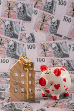 Sembolik ahşap bir ev ve 100 Çek kronu banknotuna karşılık altın bir anahtar..