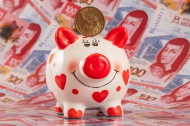 Domuz kumbarası ve 100 Meksika pesosunun arka planına karşılık bir Amerikan doları.