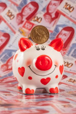 Domuz kumbarası ve 100 Meksika pesosunun arka planına karşılık bir Amerikan doları.