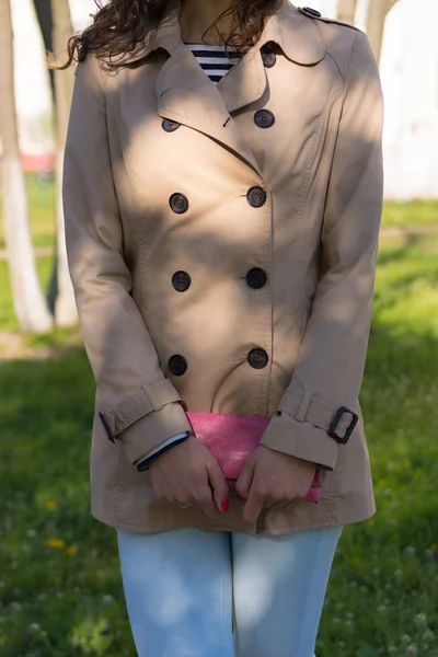 Young girl in a beige coat, blue jeans and striped t-shirt