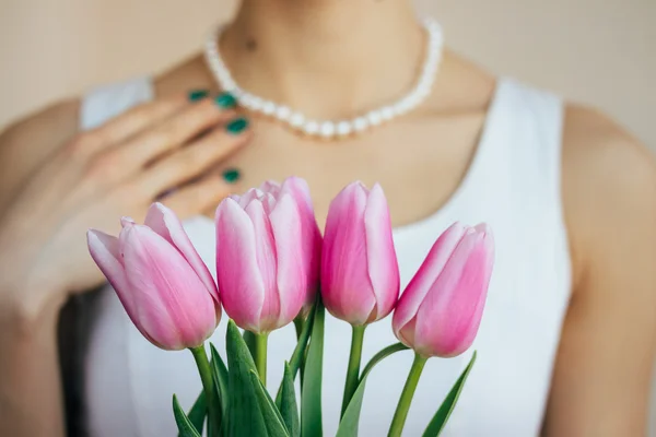 Woman in a white dress takes a gift of tulips