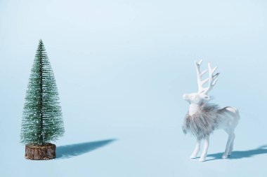 Mavi arka planda ağaç olan Noel geyiği. Yaratıcı minimalist kompozisyon.
