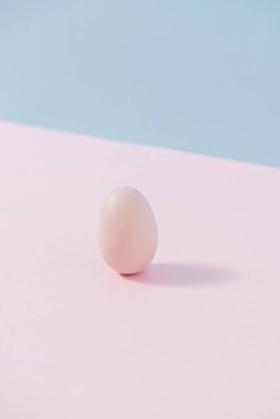 Pudra pembesi ve mavi arka planda pastel renkli yumurta. Yaratıcı kart kavramı.